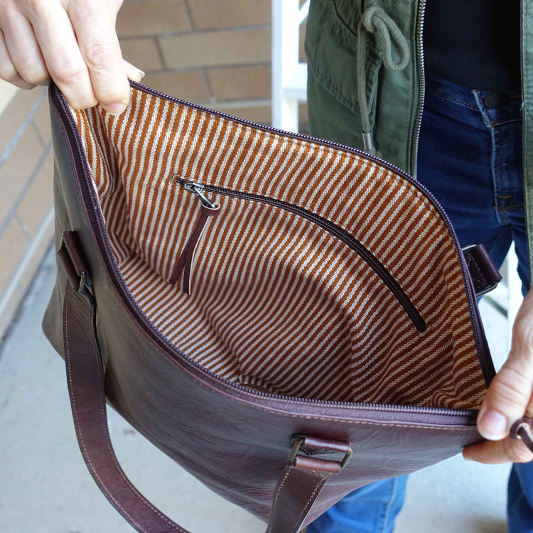 Close-up of a brown and white striped bag interior with a person holding it.